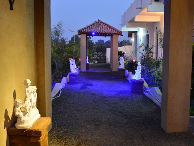 Lit garden walkway with statues at night