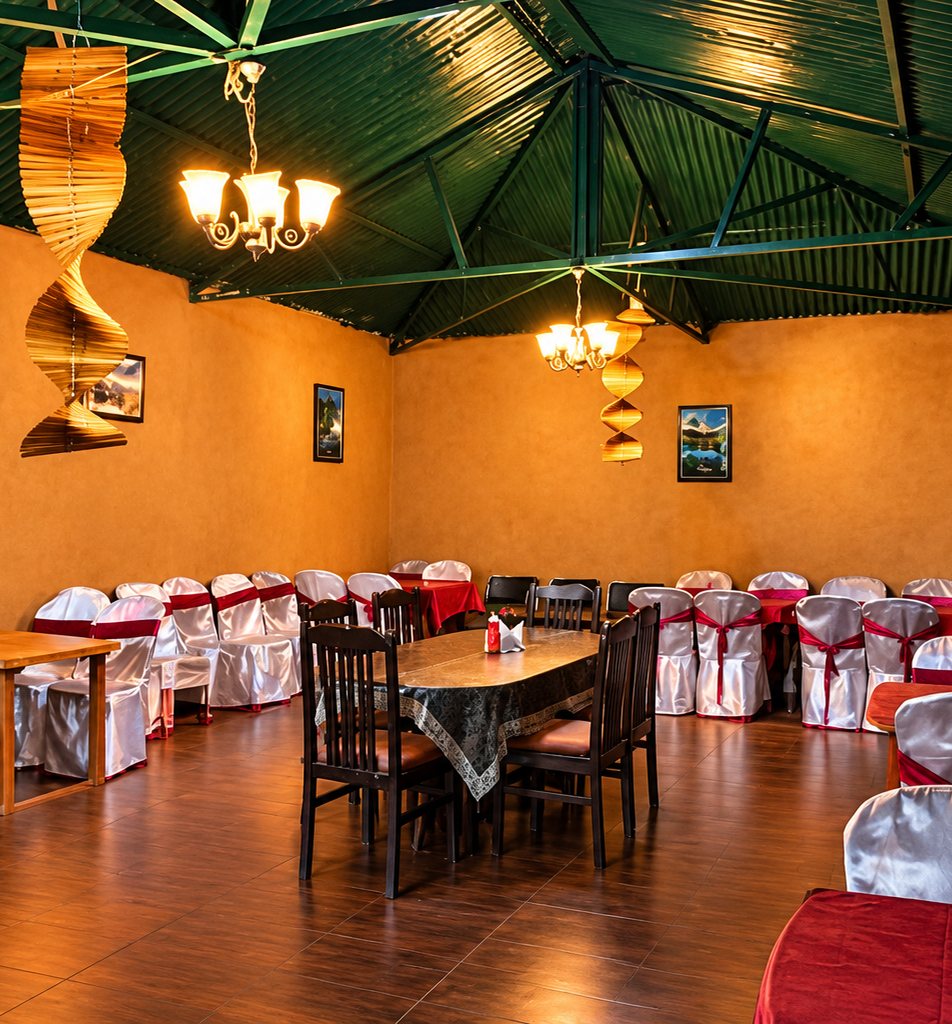 Dining hall at The Sun Resort Bandhavgarh with set tables, chandeliers and warm earthen walls